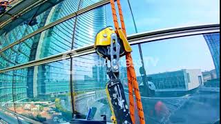 Rope access worker cleaning walls with a window squeegee [upl. by Rieth]