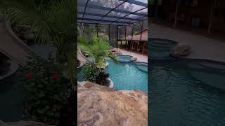 This backyard has a huge grotto a waterslide a big spa a swimup bar a screened enclosure [upl. by Igor]